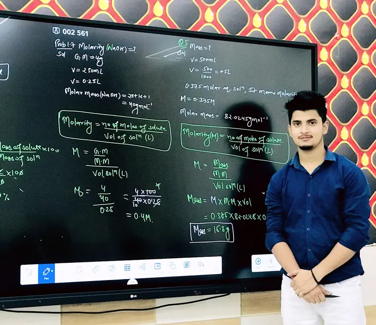 A teacher beside the smart board at Prajapati Institute, the screen covered in a worked molarity calculation