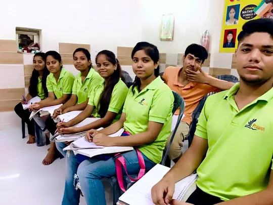 Students in institute shirts sitting with their notebooks at Prajapati Institute